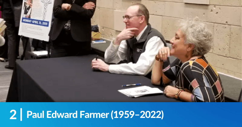 Paul Farmer, MD and Deliana Garcia (MCN) sitting behind a table. Heading reads, Paul Edward Farmer (1959-2022).