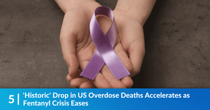 Two hands holding a purple ribbon for overdose awareness. Heading reads, 'Historic' Drop in US Overdose Deaths Accelerates as Fentanyl Crisis Eases..