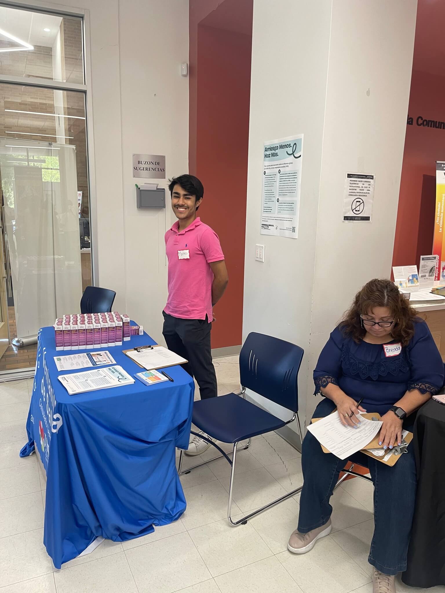 Staff smiles at the camera, while a patient fills out paperwork.