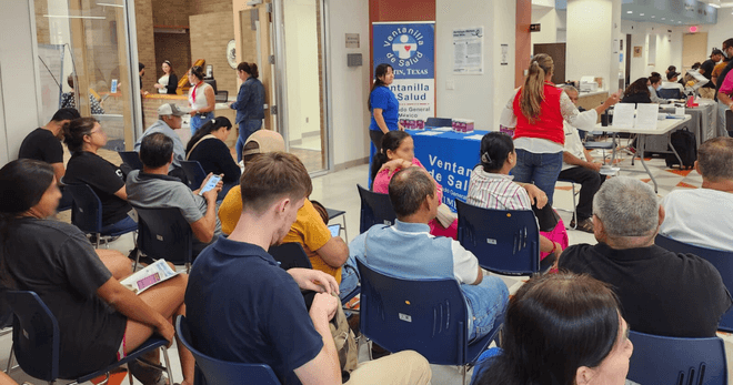 Photo of a group of attendees sitting in front of the VdS table, waiting for their vaccines.